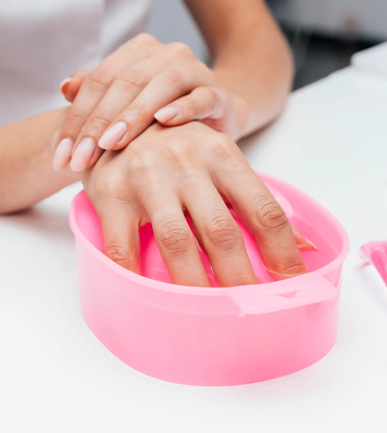 Woman soaking her hands in a gel removal solution during her Soak-Off Gel experience at Pause Spa