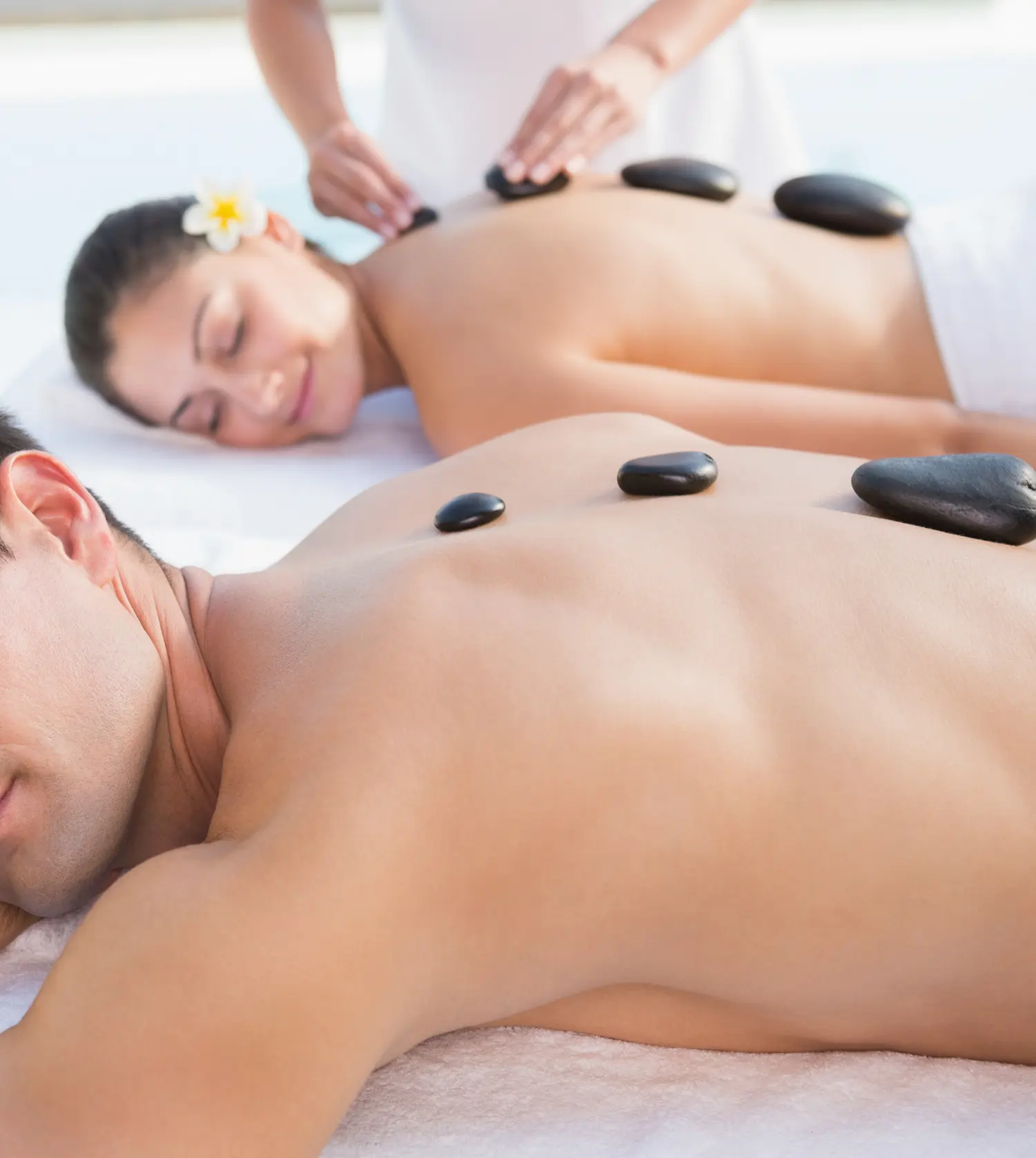 Young couple enjoying a relaxing hot stone massage together during their Hot Stone Couple's Massage experience at Pause Spa