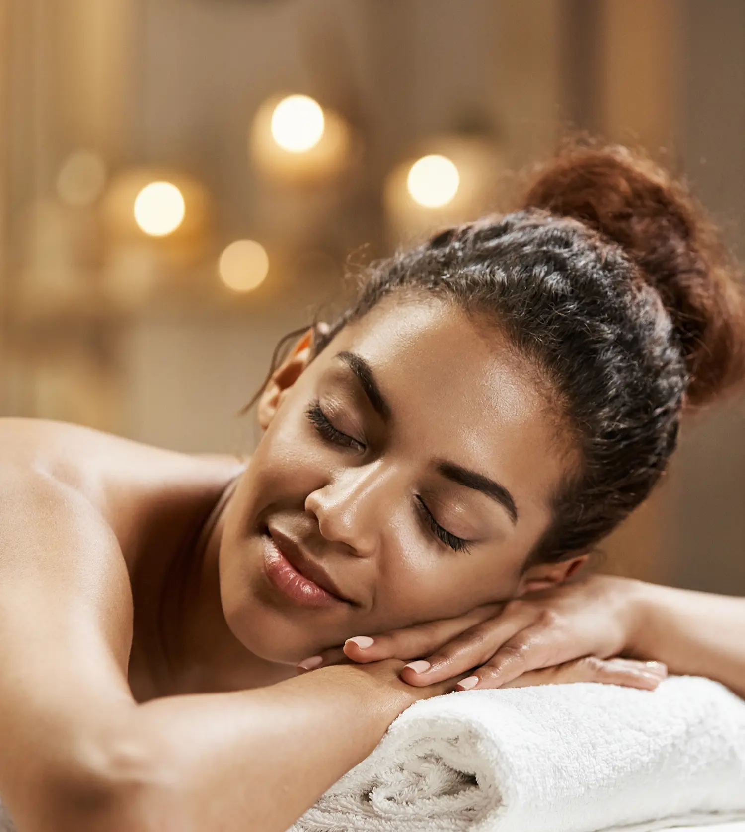 Young African woman relaxing on a massage table during her Marula Package spa experience at Pause Spa