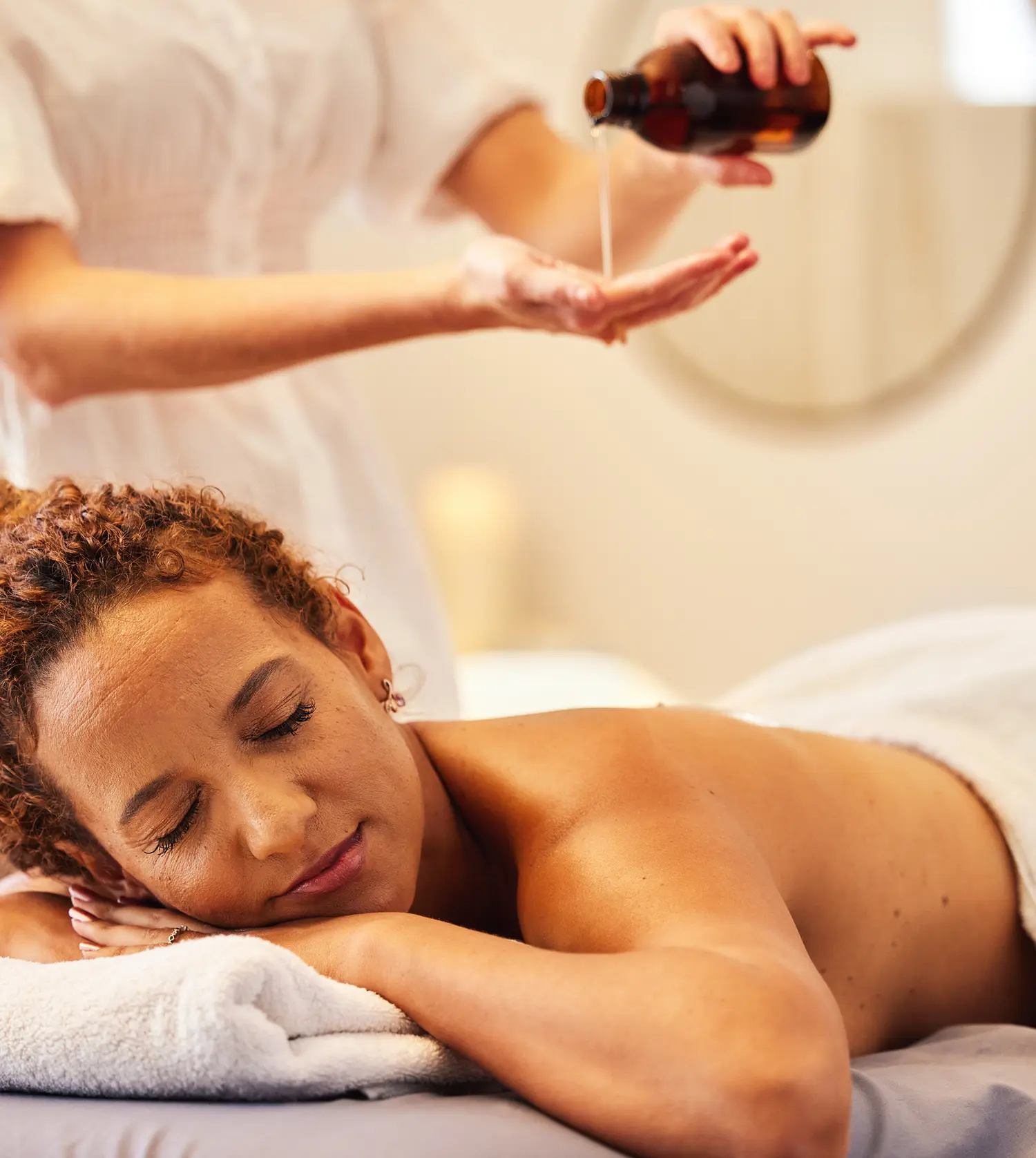 African woman enjoying an essential oil massage on a treatment table as part of the Relaxing and Hydrating Pamper Journey spa package at Pause Spa